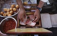 A streetside restaurant owner keeps money received from a customer in Mumbai