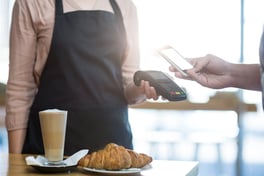 Man paying bill through smartphone using NFC technology in cafe